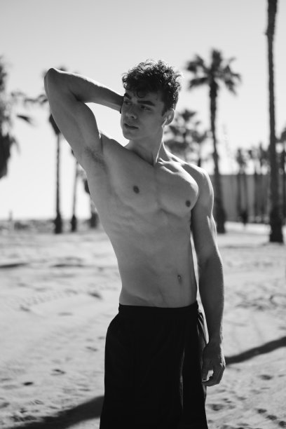 英俊的运动的家伙与躯干摆姿势在炎热的夏天在海滩上。黑白照片图片下载