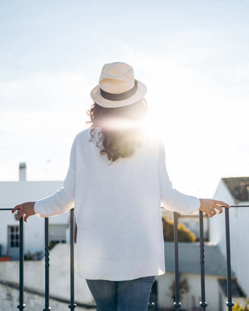 一个不认识的年轻女人，戴着帽子，从后面探出阳台图片下载
