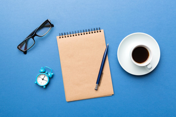现代办公桌椅，桌上备有笔记本等用品，配有咖啡杯。空白笔记本页为您设计。俯视图，平躺图片下载
