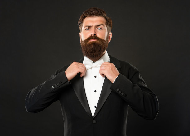 留着胡子的新郎在黑色背景燕尾服，领结图片下载