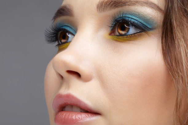 人类女性脸部特写微距镜头与黄色眼线和蓝色眼影。图片下载