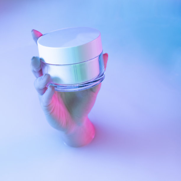 近距离的女性手拿着化妆品罐，在霓虹灯下从牛奶浴中显现出柔和的白光。贝蒂，化妆品，时尚，艺术图片下载