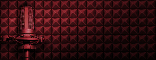 暗红色播客或录音工作室背景与声学泡沫和黑色麦克风。带有复制空间的音频横幅。图片下载