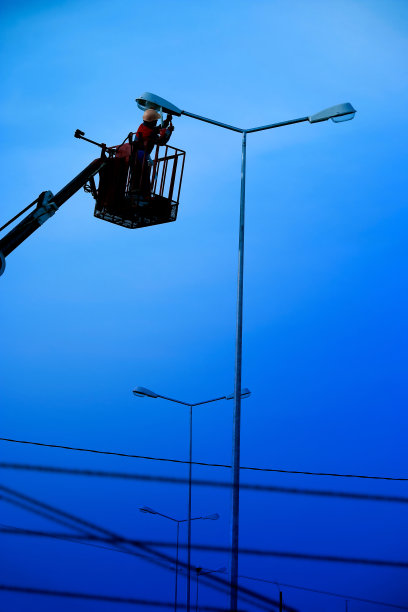 技术人员在一个挂在路灯杆上的吊桶里工作图片下载