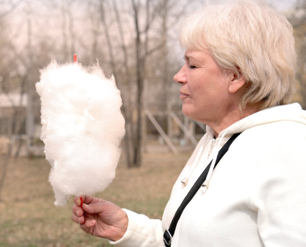 一幅在游乐园吃棉花糖的快乐老年妇女的画像图片下载