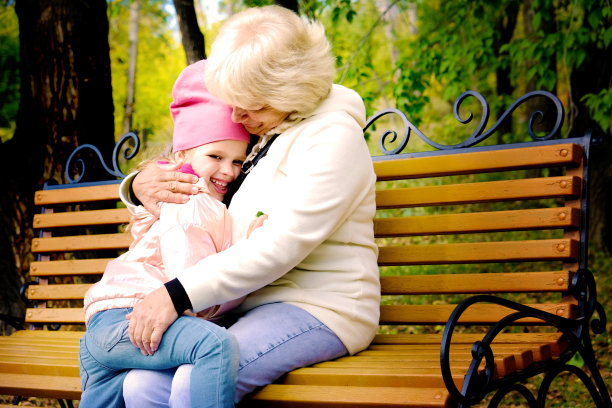 奶奶和她的孙女坐在公园的长椅上拥抱交谈。健美的图片下载