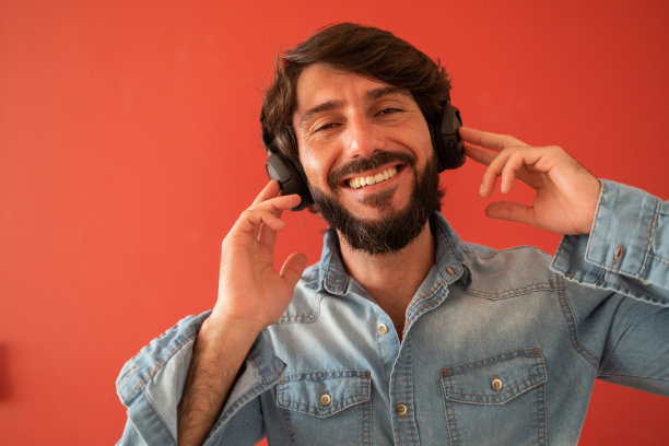 侧视图的年轻人听音乐与耳机在他的耳朵在窗口与城市景观的背景。高质量的照片图片下载