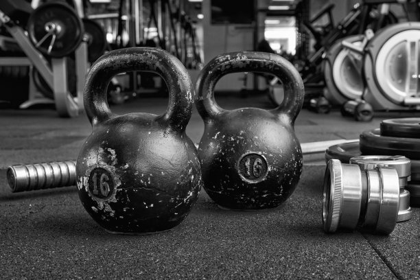 地板上的哑铃和壶铃。健身设备。有健身或健美概念背景。黑白摄影图片下载