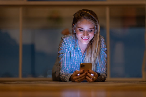 年轻人在夜晚使用智能手机的前视图，城市景观在背景中。高质量的照片图片下载