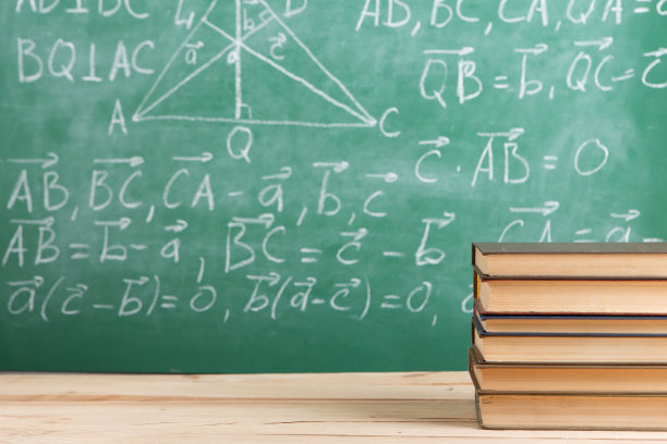 教育和阅读概念-木桌上的一组书籍，绿色的黑板，背景上有公式。老师的桌子上图片下载