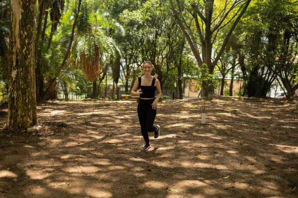 一个在户外公园跑步的年轻女子。女运动员在锻炼时。高质量的照片图片下载