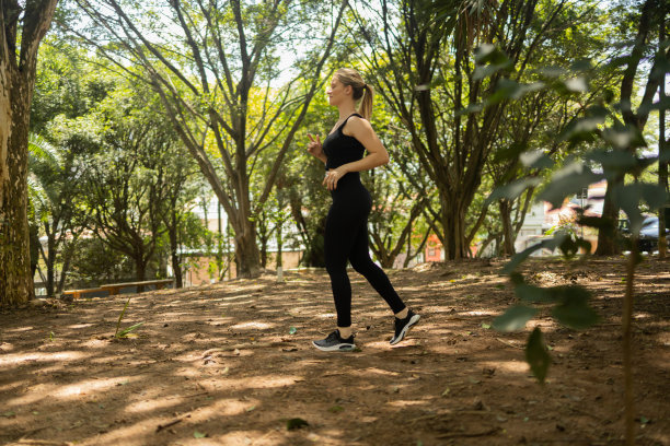 一个在户外公园跑步的年轻女子。女运动员在锻炼时。高质量的照片图片下载