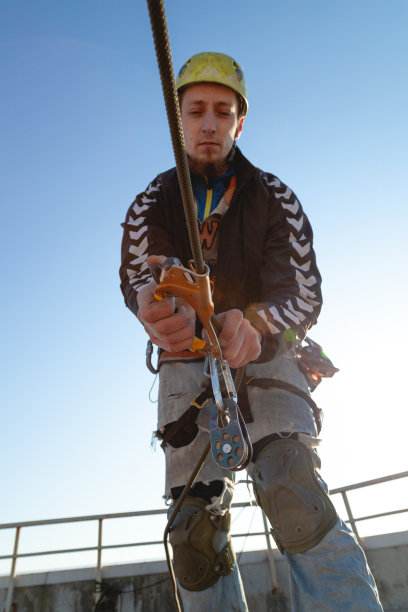 工业攀爬者在阳光下安装一个下降装置图片下载