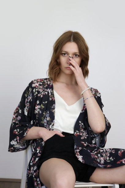 女模特穿着基本的白色丝绸上衣，黑色牛仔短裤广告花长袍。舒适的经典夏季时尚。影棚拍摄。影棚拍摄。图片下载