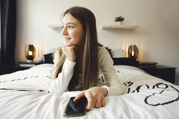 一个十几岁的女孩把智能手机放在床上图片下载