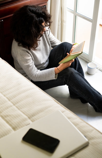放松的女人坐在地板上读小说，喝着咖啡图片下载