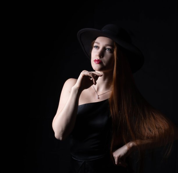 一个长头发的女孩的肖像，戴着帽子，在一个黑色的背景图片下载