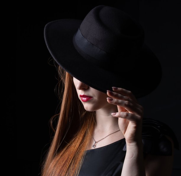 一个长头发的女孩的肖像，戴着帽子，在一个黑色的背景图片下载