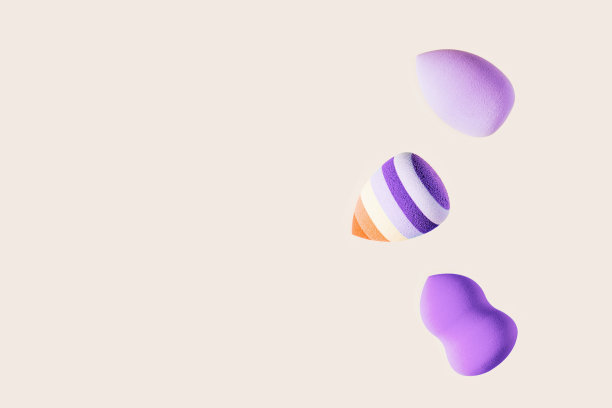 化妆海绵紫色和明亮的条纹。柔软化妆海绵美容搅拌器，脸部化妆刷，面部涂抹器。背景为沙龙时尚美容化妆。关闭膨化不同的形状图片下载