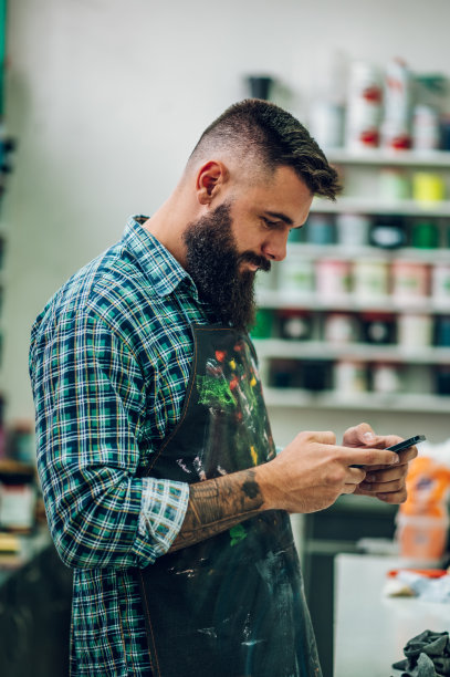 男工人在车间里用智能手机为丝网印刷调色图片下载