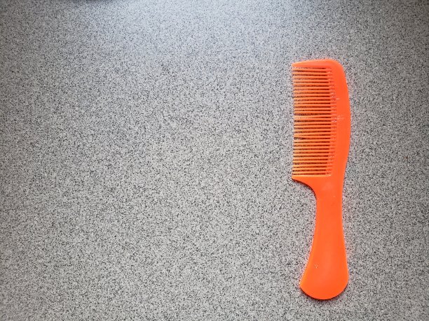 接近小橘色头发梳在灰色陶瓷背景图片下载