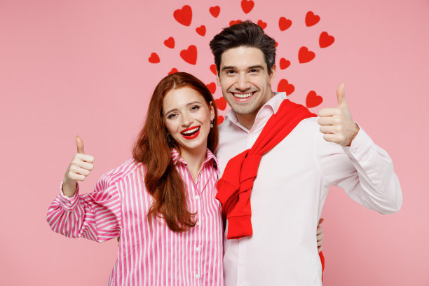 年轻的夫妇，两个朋友，女人，男人在休闲衬衫看相机显示大拇指的姿势，拥抱孤立在素色的淡粉色背景的工作室肖像。情人节生日节日派对的概念图片下载