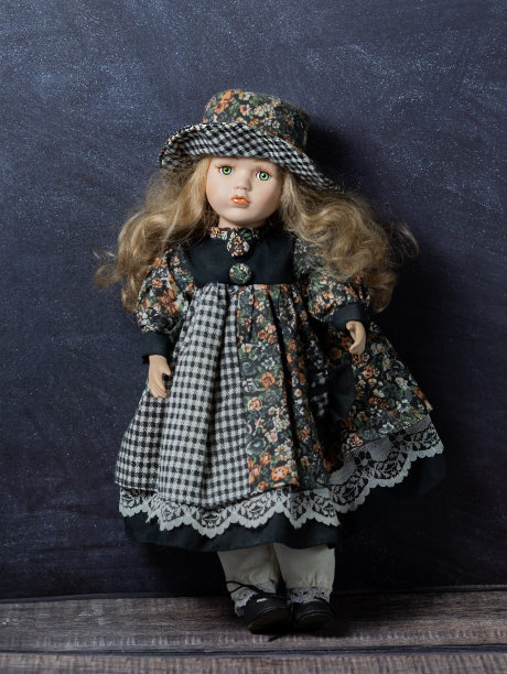 在黑色的背景上老式的瓷娃娃。时间的概念。股票的照片。优雅的礼服。一顶帽子。图片下载