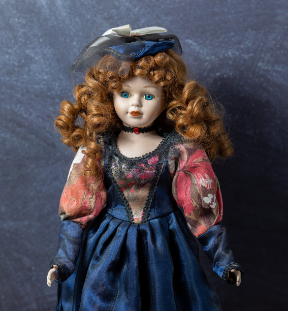 在黑色的背景上老式的瓷娃娃。时间的概念。股票的照片。优雅的礼服。一顶帽子。图片下载