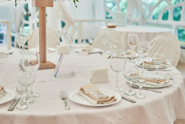 餐桌设置起泡的酒杯，盘子米色餐巾和餐具在桌子上，复制空间。在婚宴上放置。餐厅婚宴餐桌图片下载
