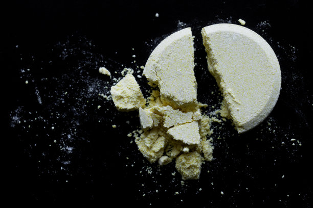 一个黄色的大药丸，分成两半，躺在黑色的背景上。宏图片下载