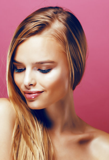 年轻漂亮的金发真实的女人与发型接近和粉红色的背景微笑的化妆图片下载