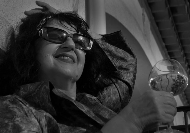 那个女人坐在阳台上，手里拿着一杯饮料，玩得很开心图片下载