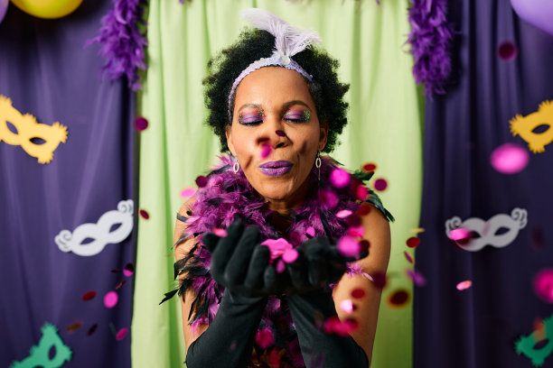 黑人妇女在庆祝狂欢节时吹着五彩纸屑。图片下载