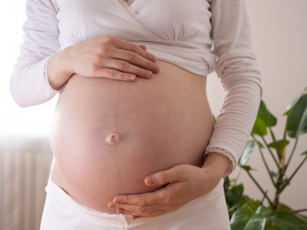 正面看孕妇触摸她裸露的腹部抚摸她的皮肤，皮肤和身体护理图片下载