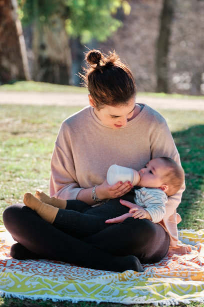 一名年轻女子在公园外面用奶瓶喂她的儿子图片下载