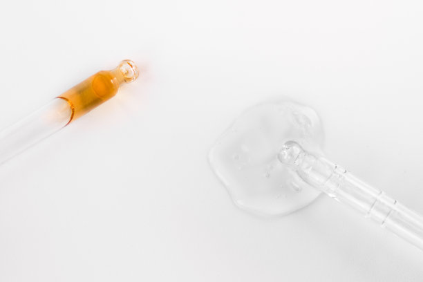 两个移液器在单色灰色背景上显示透明质酸。化妆品和保健概念特写图片下载