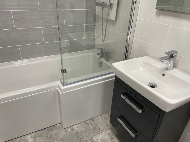 现代浴室的形象，白色的独立陶瓷水槽和黑色的单杠杆整体水龙头，白色的浴缸与黑色的侧板，黑色的梳妆台，灰色的石头地砖图片下载