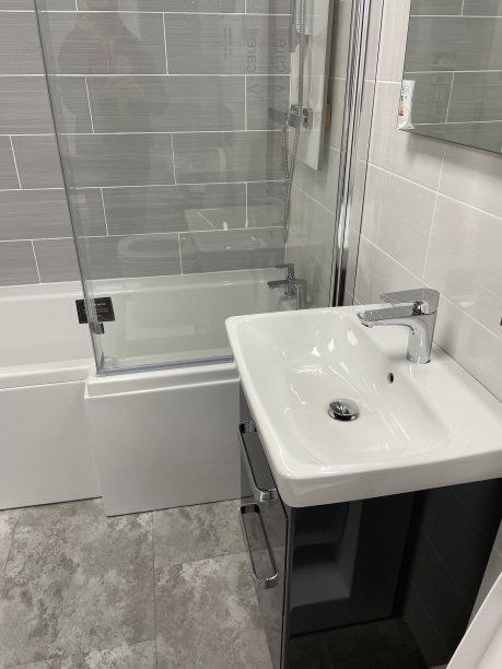 现代浴室的形象，白色的独立陶瓷水槽和黑色的单杠杆整体水龙头，白色的浴缸与黑色的侧板，黑色的梳妆台，灰色的石头地砖图片下载