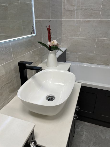 现代浴室的形象，白色的独立陶瓷水槽和黑色的单杠杆整体水龙头，白色的浴缸与黑色的侧板，黑色的梳妆台，灰色的石头地砖图片下载