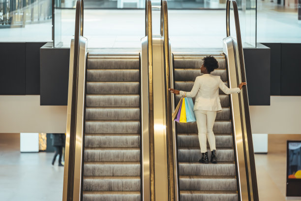 时髦的女人独自乘坐下行自动扶梯图片下载