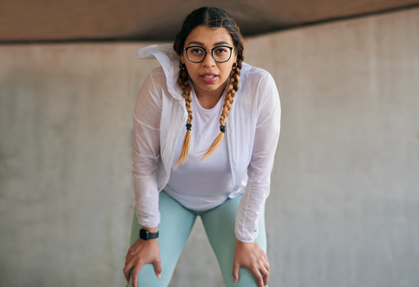 一个运动的年轻女子的肖像捕捉她的呼吸，而户外锻炼图片下载