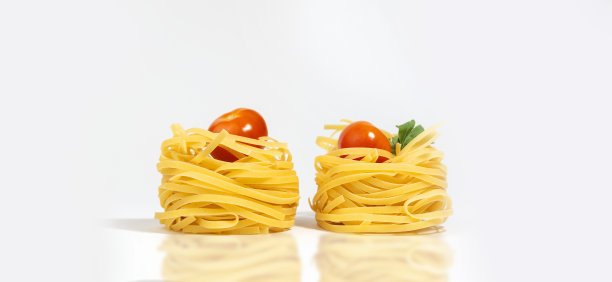 意大利面食。意大利细面条，樱桃番茄和绿色蔬菜，孤立在一个白灰色的背景与硬阴影和反射。巢状的意大利面。意面的创意照片。横幅图片下载
