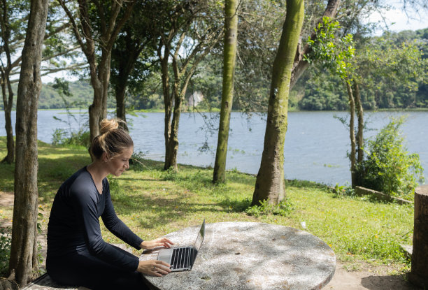 年轻人在白天使用智能手机，背景是一个绿色的公园。高质量的照片图片下载