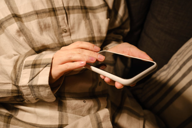 女孩在舒适的床上拿着智能手机，在睡前或醒来后查看社交网络账号。小玩意上瘾。女人用手机发短信图片下载