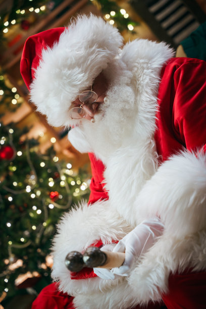 圣诞老人坐在装饰华丽的房间里，打开一卷写着孩子们名字的卷轴图片下载