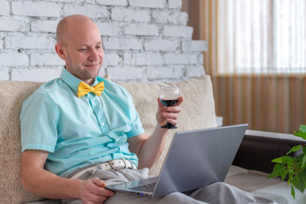 虚拟假日。优雅的男士穿着衬衫，打着领结，端着一杯红酒，通过电话进行在线约会。快乐的人说祝酒词，并在自我隔离的情况下远程视频聊天庆祝节日。爱在封锁。图片下载