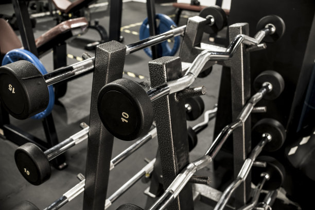 在健身房或健身俱乐部中放置有固定重量的EZ和直杠杠铃的架子。图片下载