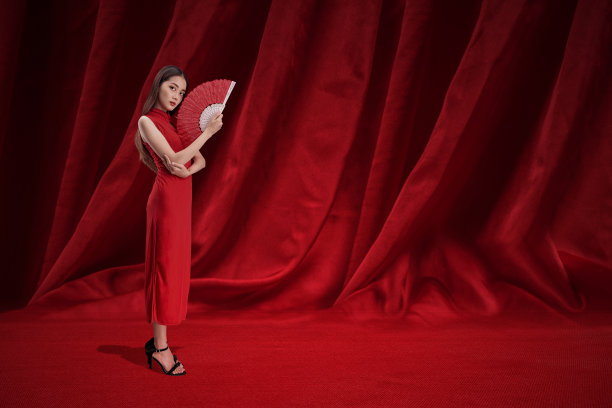 亚洲的中国妇女穿着旗袍，拿着扇子庆祝中国新年图片下载