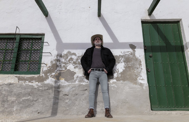 一个戴着牛仔帽和牛仔裤的男人靠墙的肖像。西班牙阿尔梅里亚图片下载