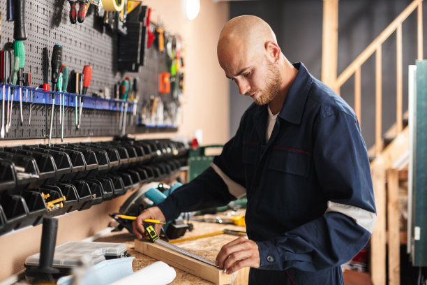 年轻的领班穿着工作服，用卷尺测量工作时间图片下载